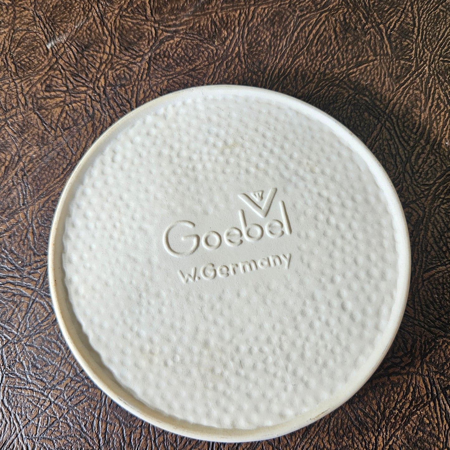 White ceramic plate with 'Goebe' branding on a textured brown surface