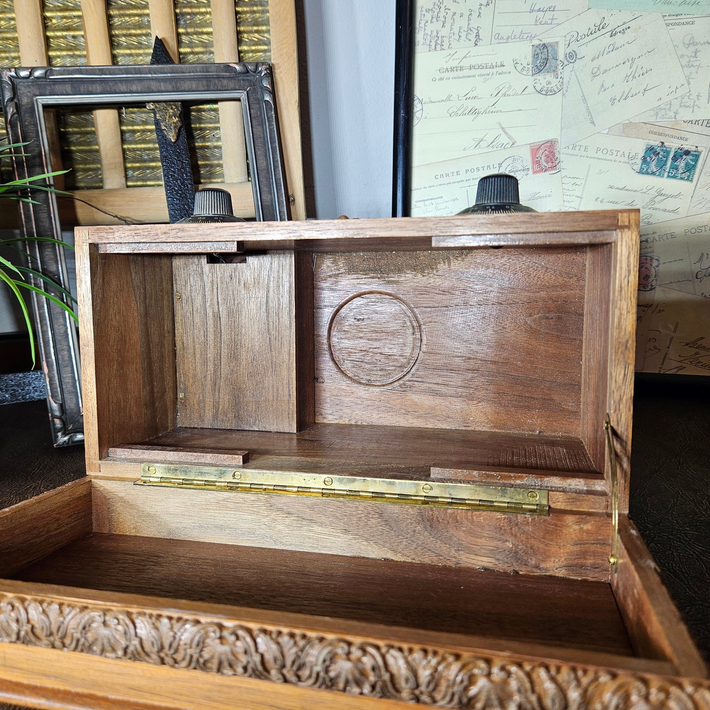 Wooden music box with a lid open, displaying a circular engraving, on a textured surface.