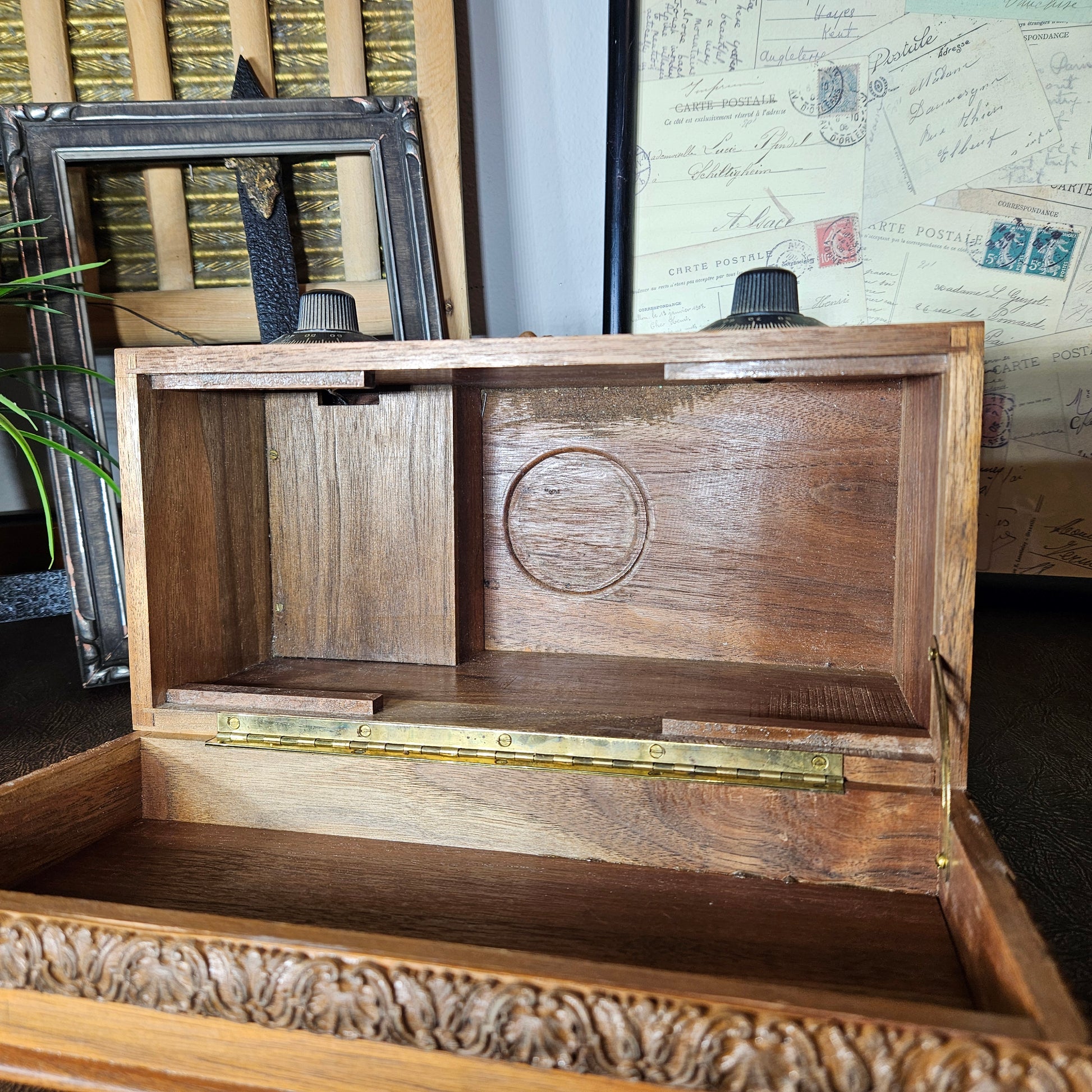 Wooden music box with a lid open, displaying a circular engraving, on a textured surface.