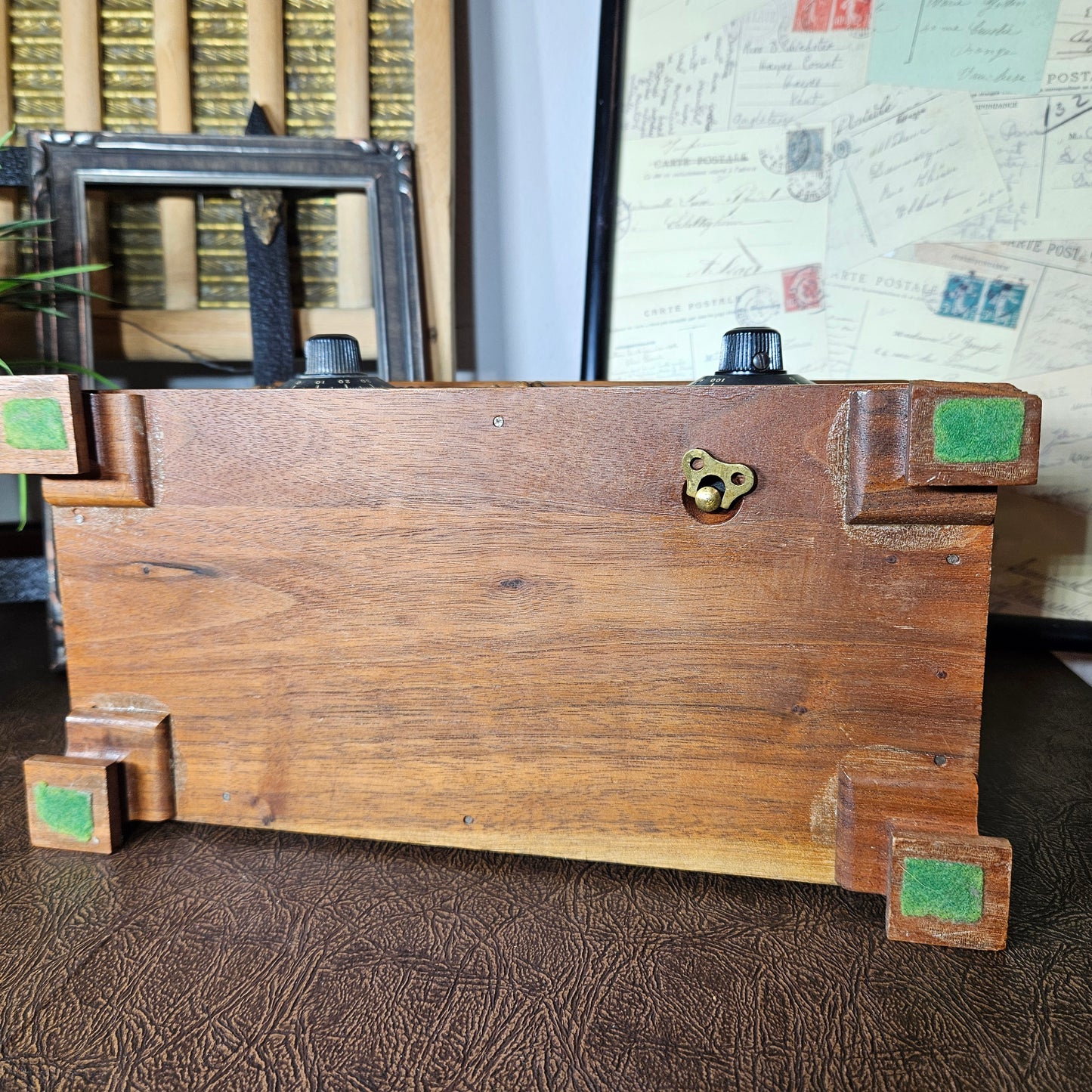 Wooden music box with green corner caps on a textured surface