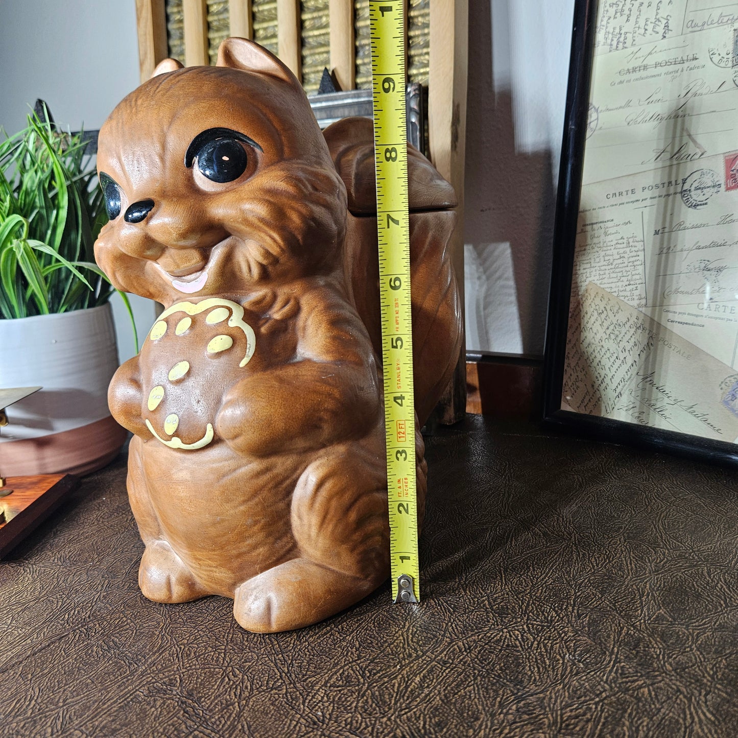 Ceramic squirrel figurine cookie jar with measuring tape for scale
