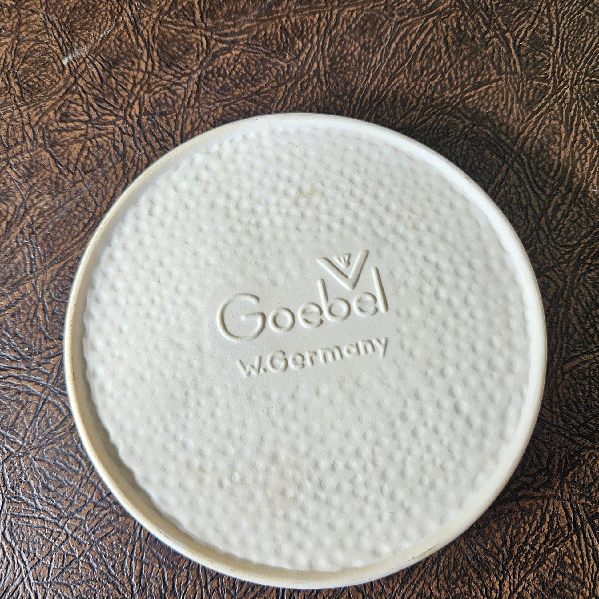 White ceramic plate with 'Goebe' branding on a textured brown surface