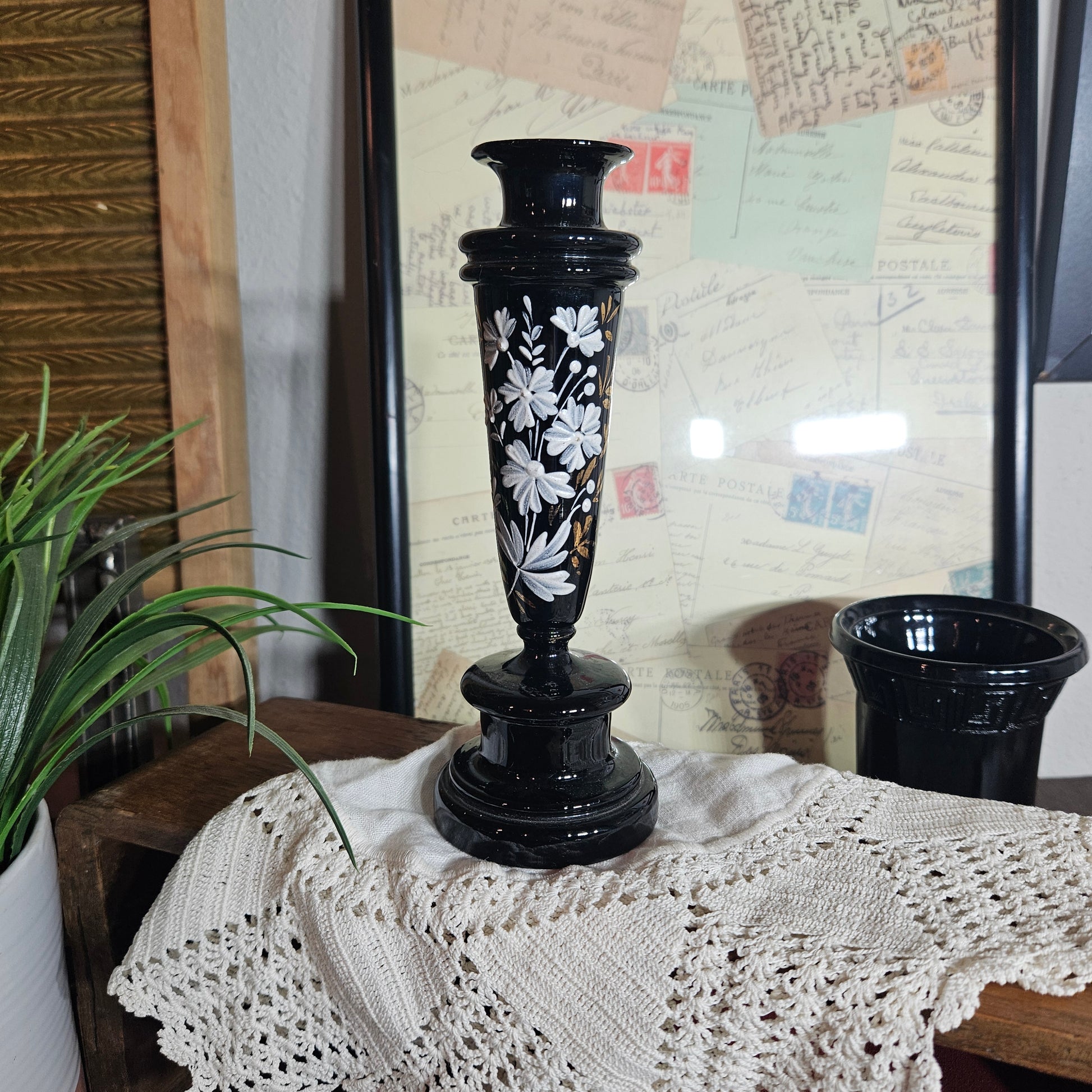 Decorative black candlestick with white floral patterns on a textured surface.