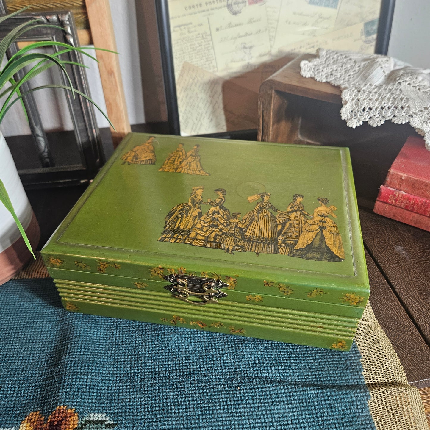 Green decorative box with gold embossed design on a textured surface