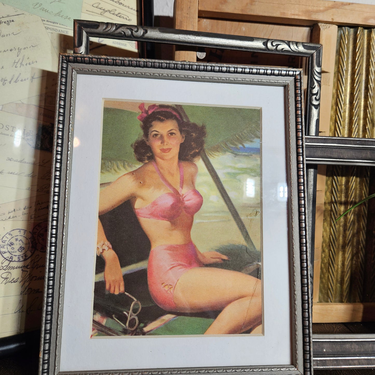 Framed vintage-style poster of a woman in a pink swimsuit on a wooden surface.