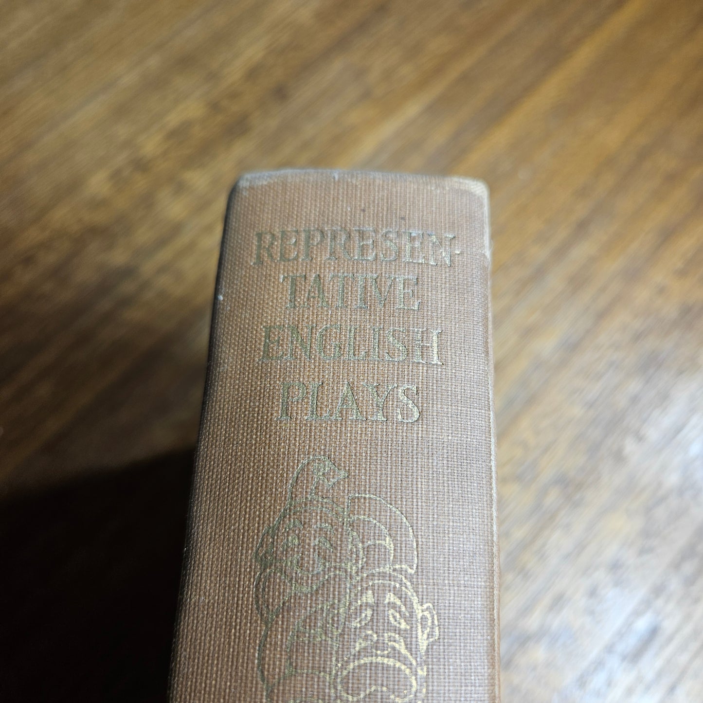 Close-up of a book spine with embossed text and a logo on a wooden surface