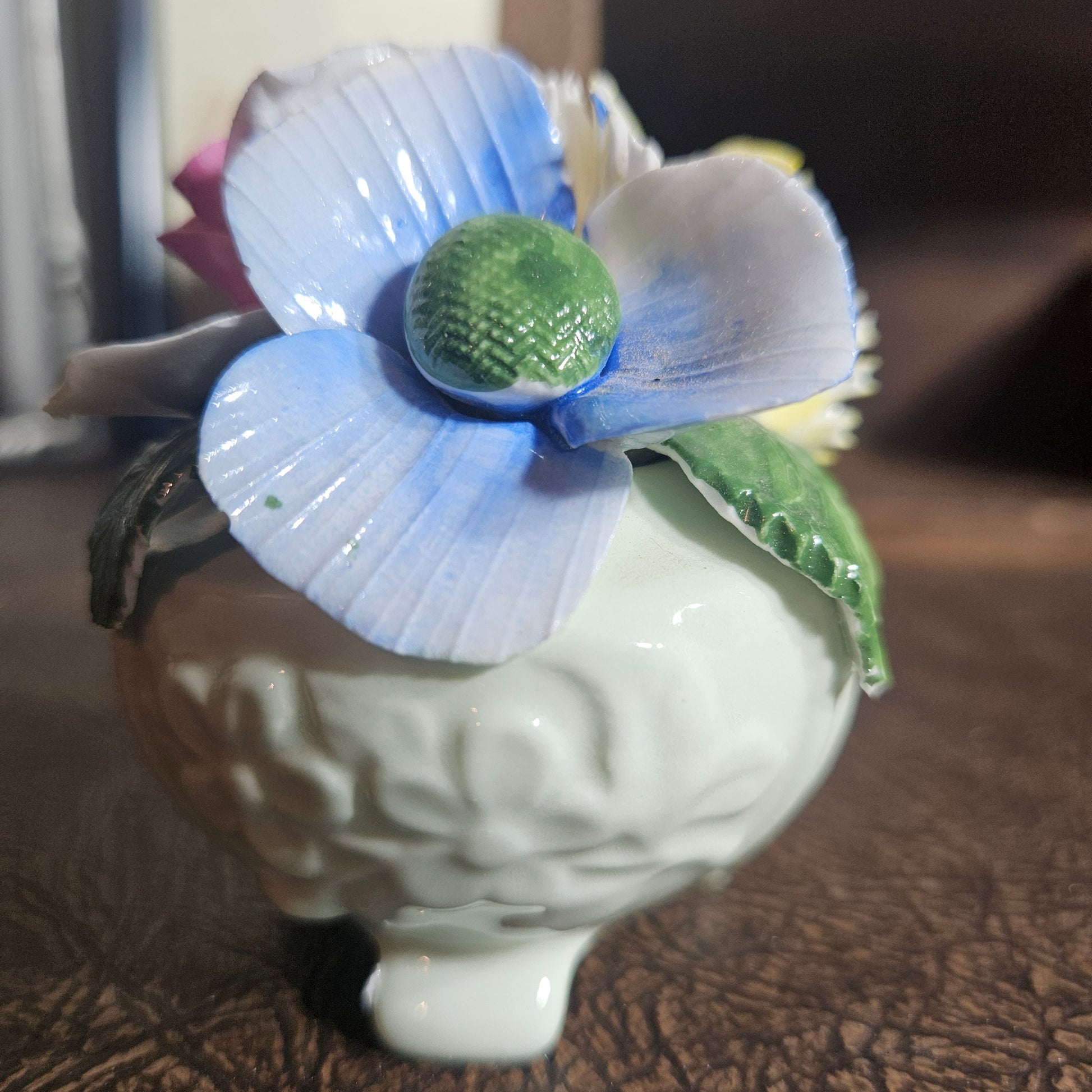 Ceramic sculpture of a face with a blue flower. forever flowers. permanent flowers