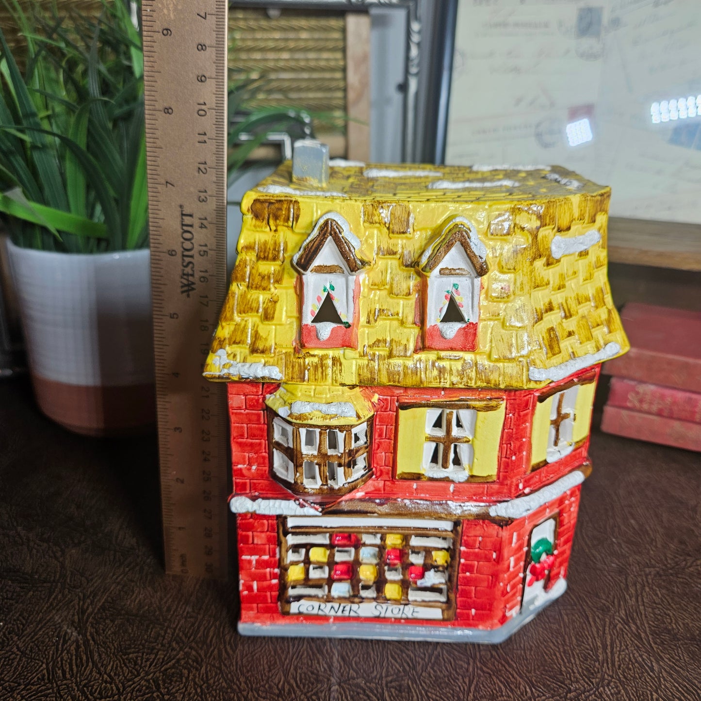Decorative gingerbread house with a ruler for scale on a wooden surface