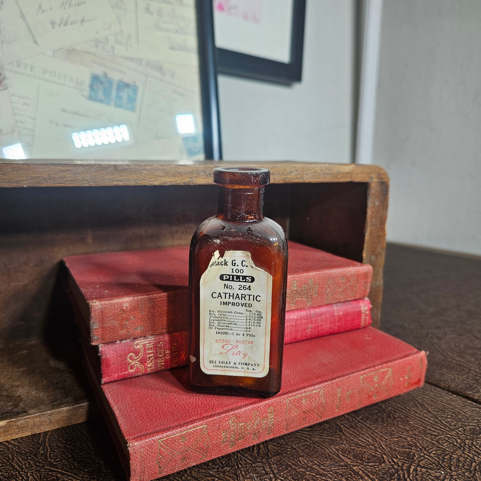 Vintage bottle of medicine on top of a red book in a wooden box.