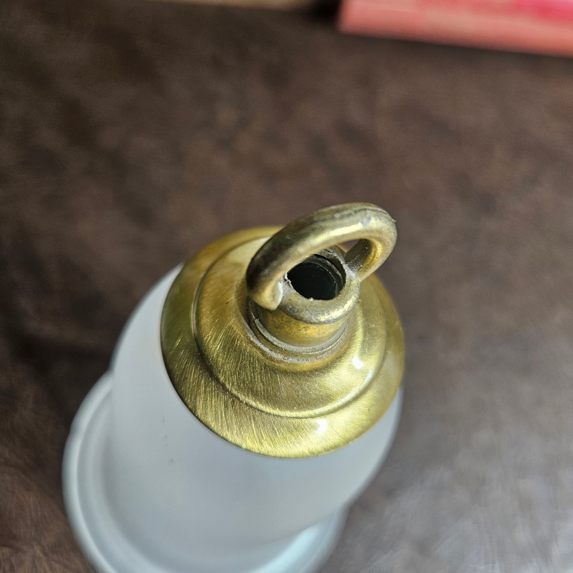 Close-up of a brass fitting on a white object against a brown background