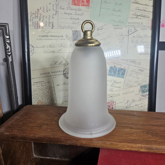 White cylindrical lamp shade with a gold ring on a textured surface