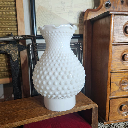 White textured vase on a wooden surface with a wooden cabinet in the background