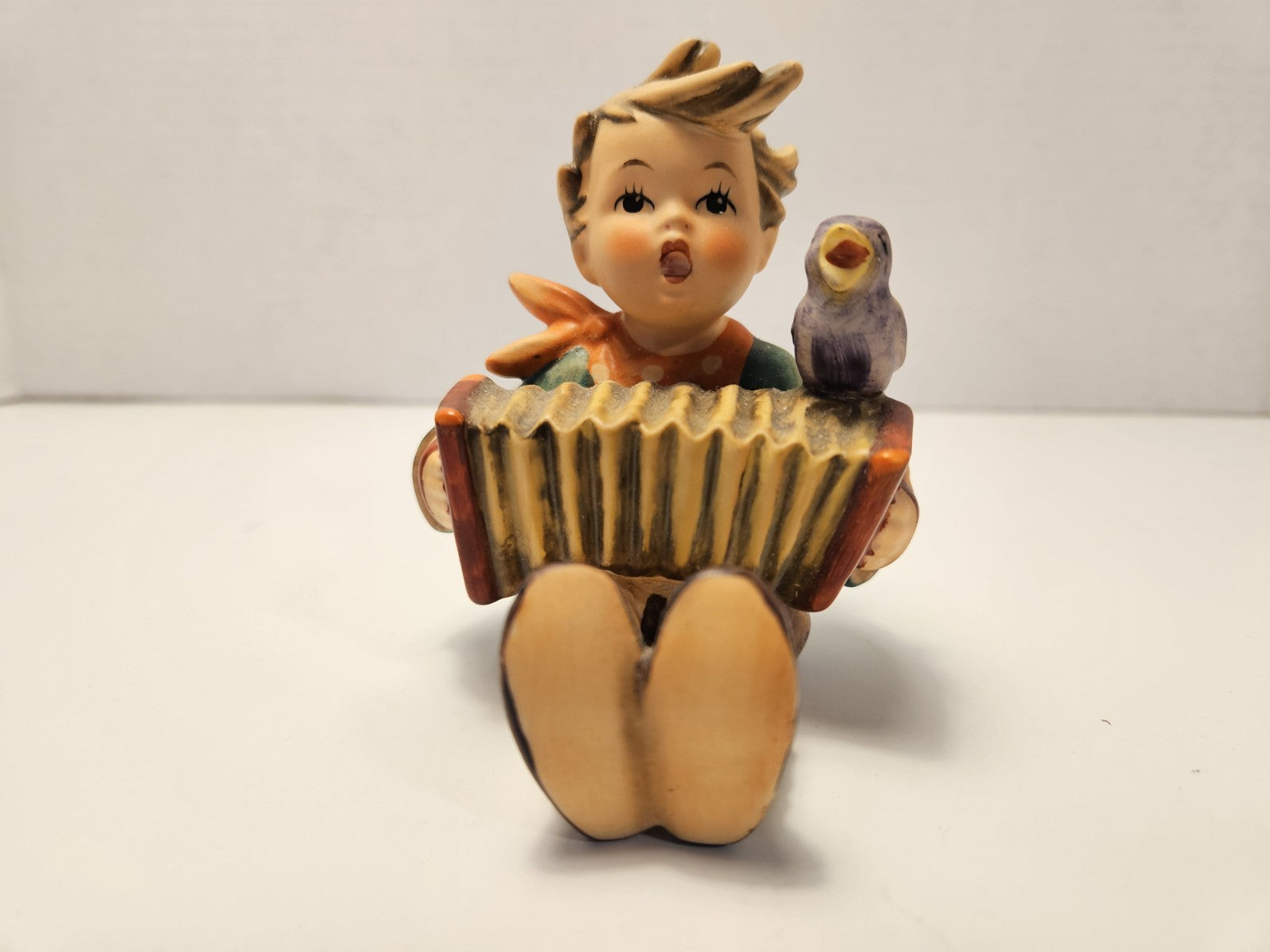 Figurine of a boy playing an accordion on a white background music