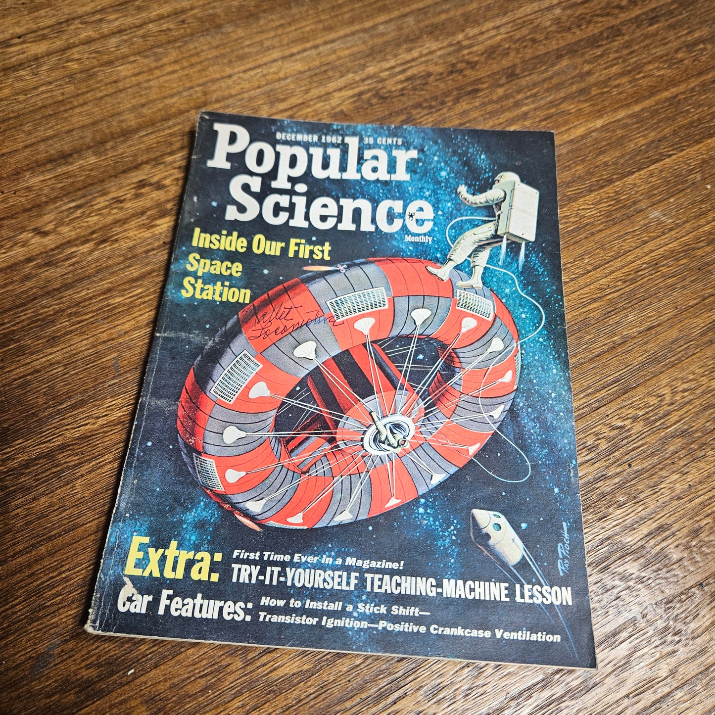 Book cover of 'Popular Science' featuring a space station illustration on a wooden surface