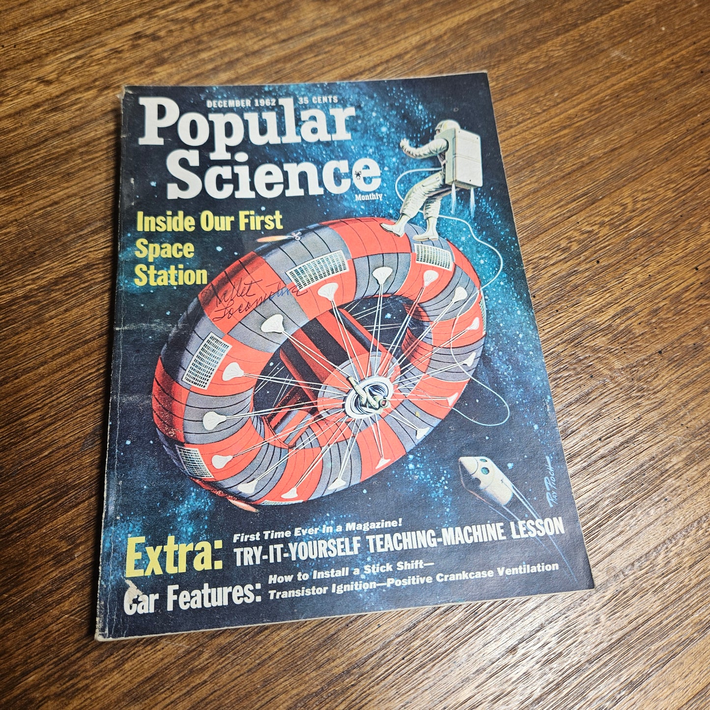 Vintage 'Popular Science' magazine cover with space station illustration on a wooden surface