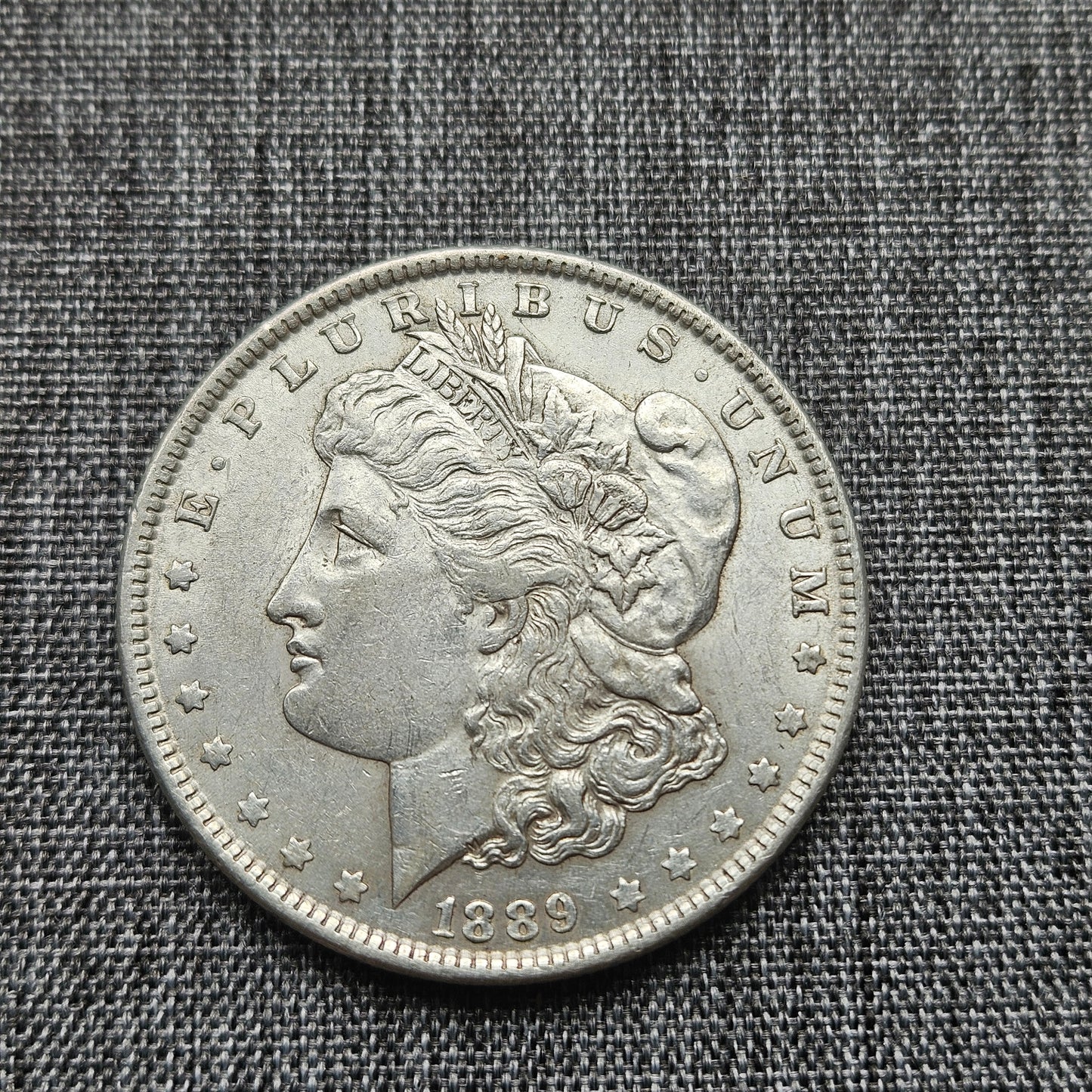 Silver coin with a profile of a woman and 'E Pluribus Unum' text on a textured gray background