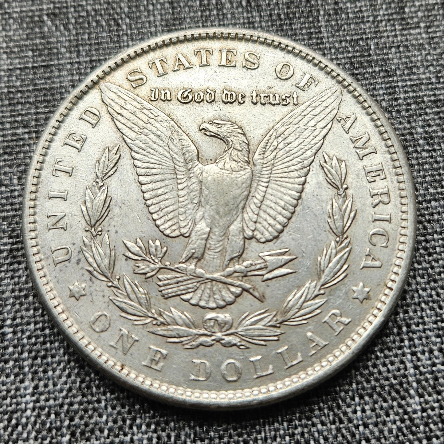 Silver dollar coin with an eagle design on a textured gray fabric background