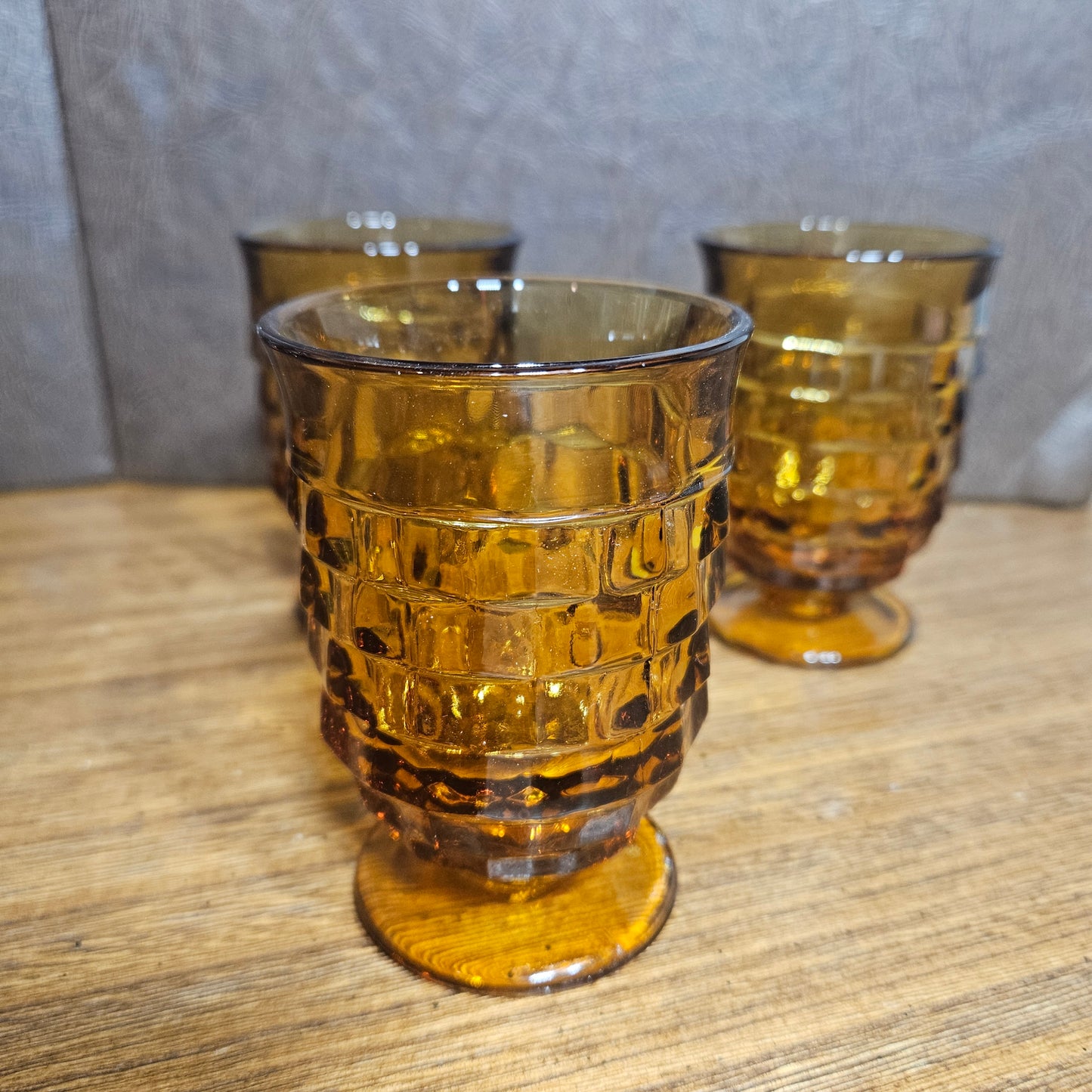 Set of amber glass tumblers with textured design on a wooden surface